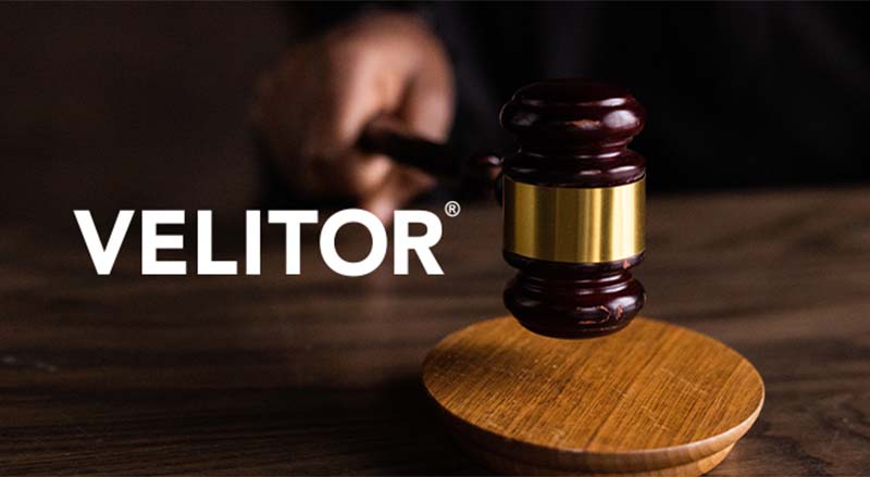 Velitor logo over hand holding gavel and block in Velitor Landmark case