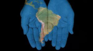 Open palm hand gesture in blue color with South America image overlay.